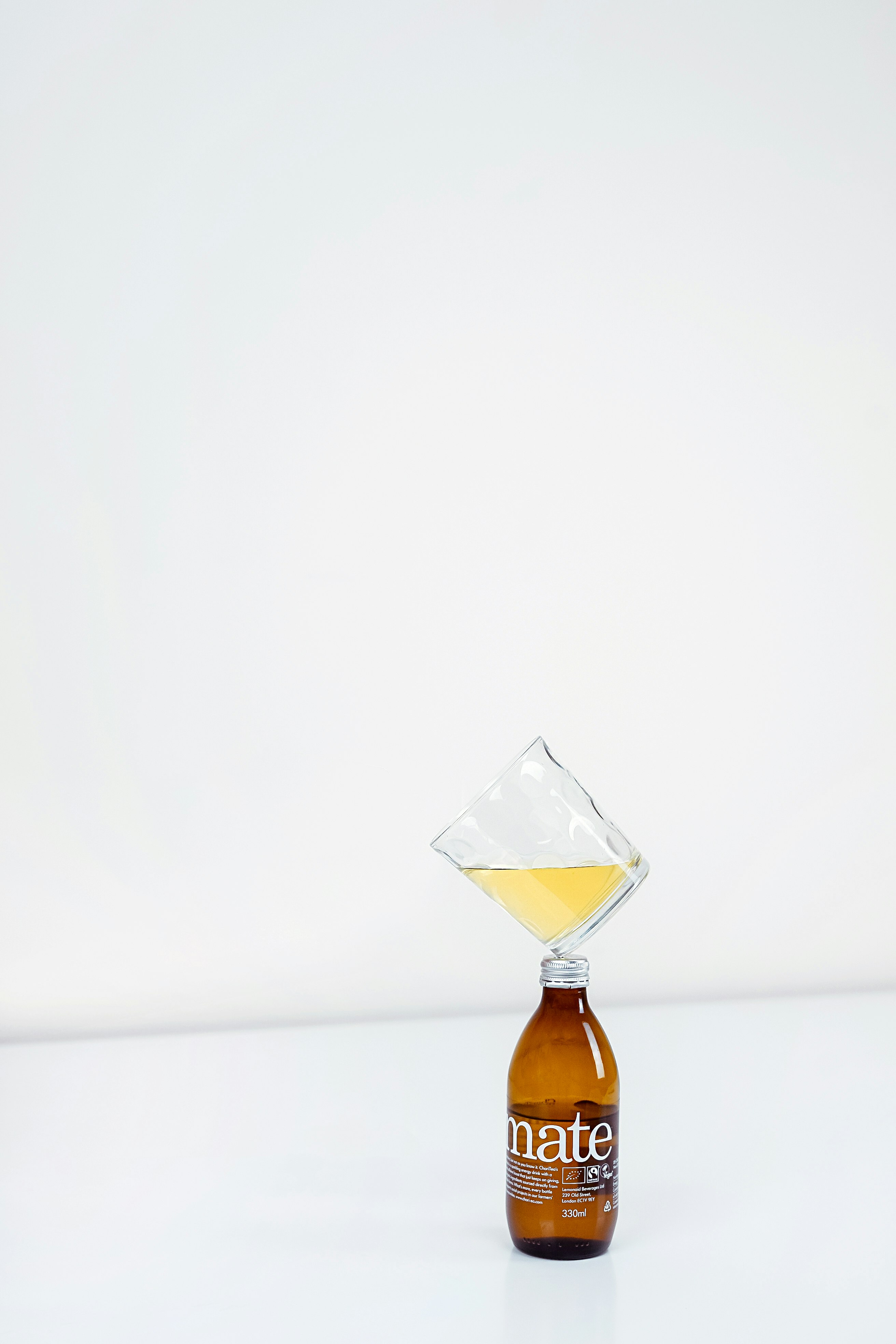 1/4 full clear drinking glass on top of amber bottle